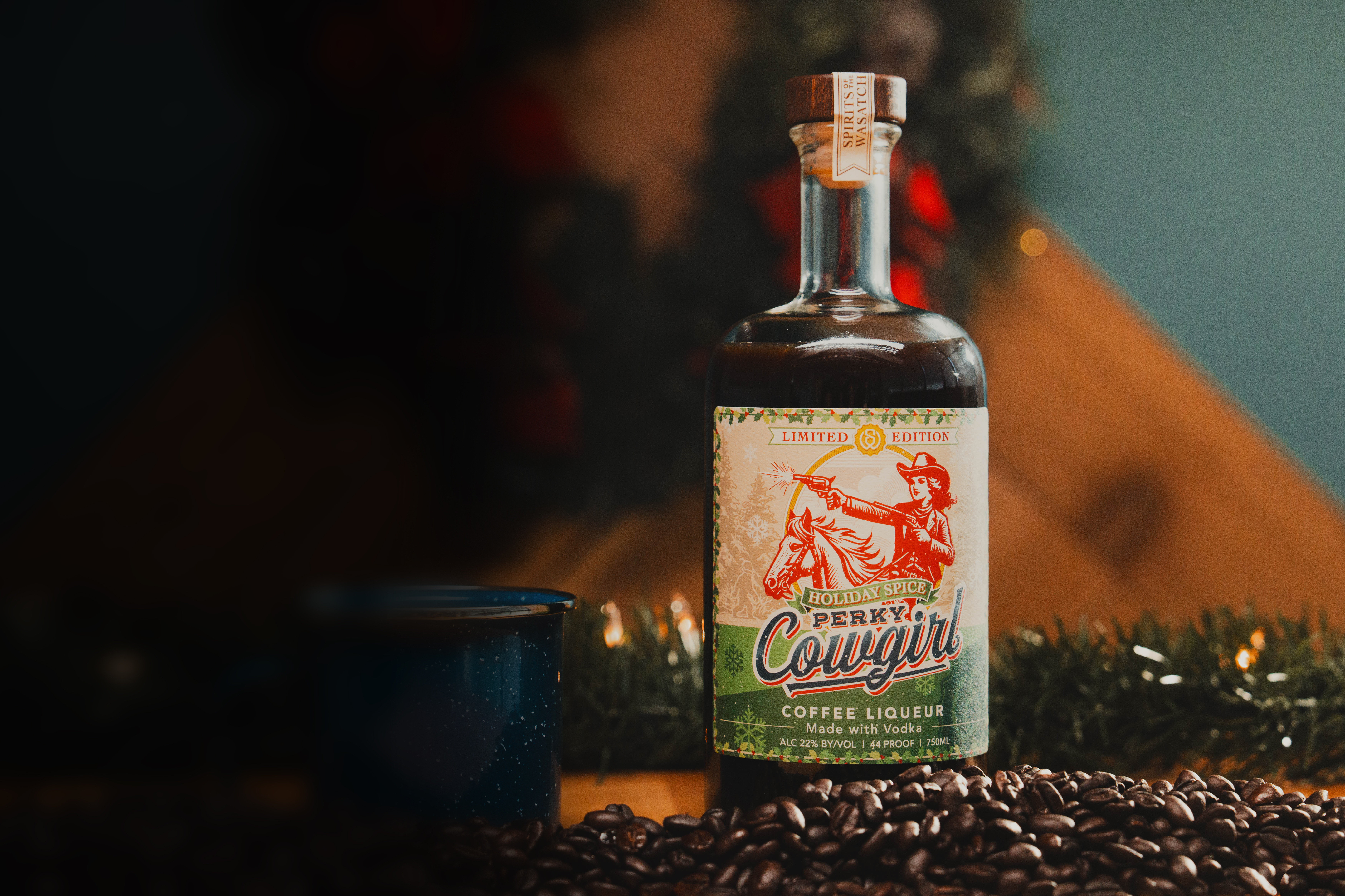 Perky Cowgirl Coffee Liqueur: Holiday Spice Bottle - Professionally photographed. Sitting atop an aging barrel with coffee beans.